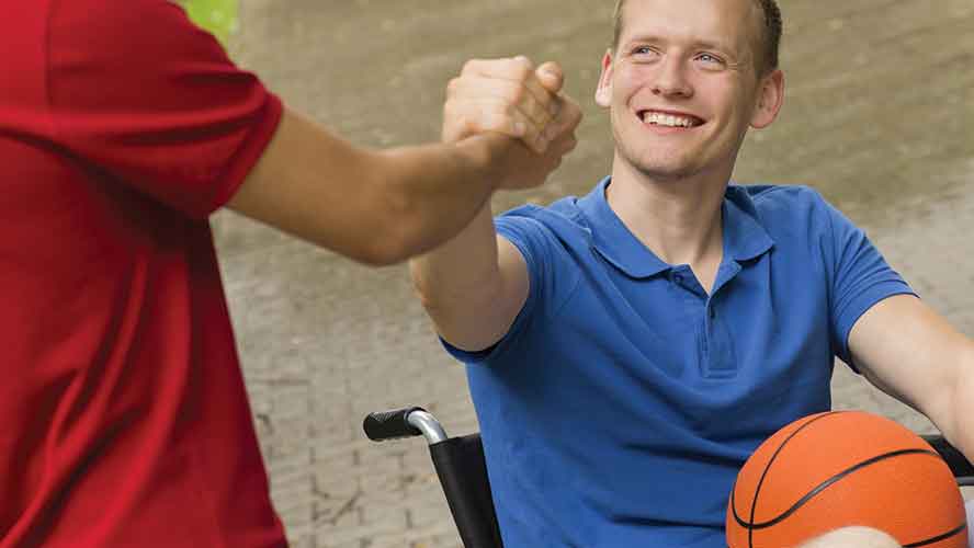 man in wheelchair with basketball shaking teammate hand