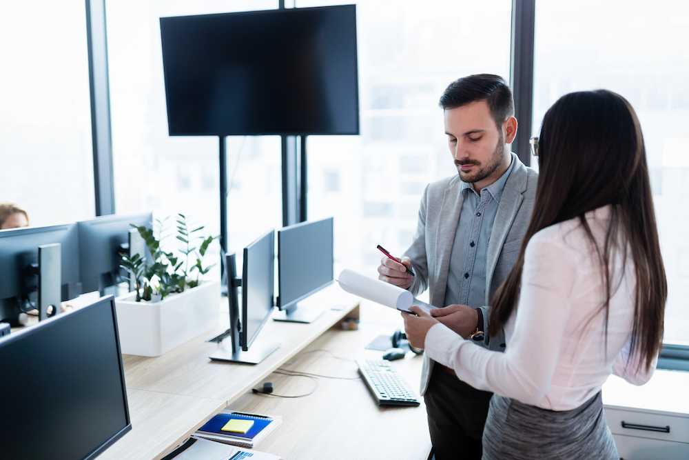 two work colleagues standing and reviewing paperwork
