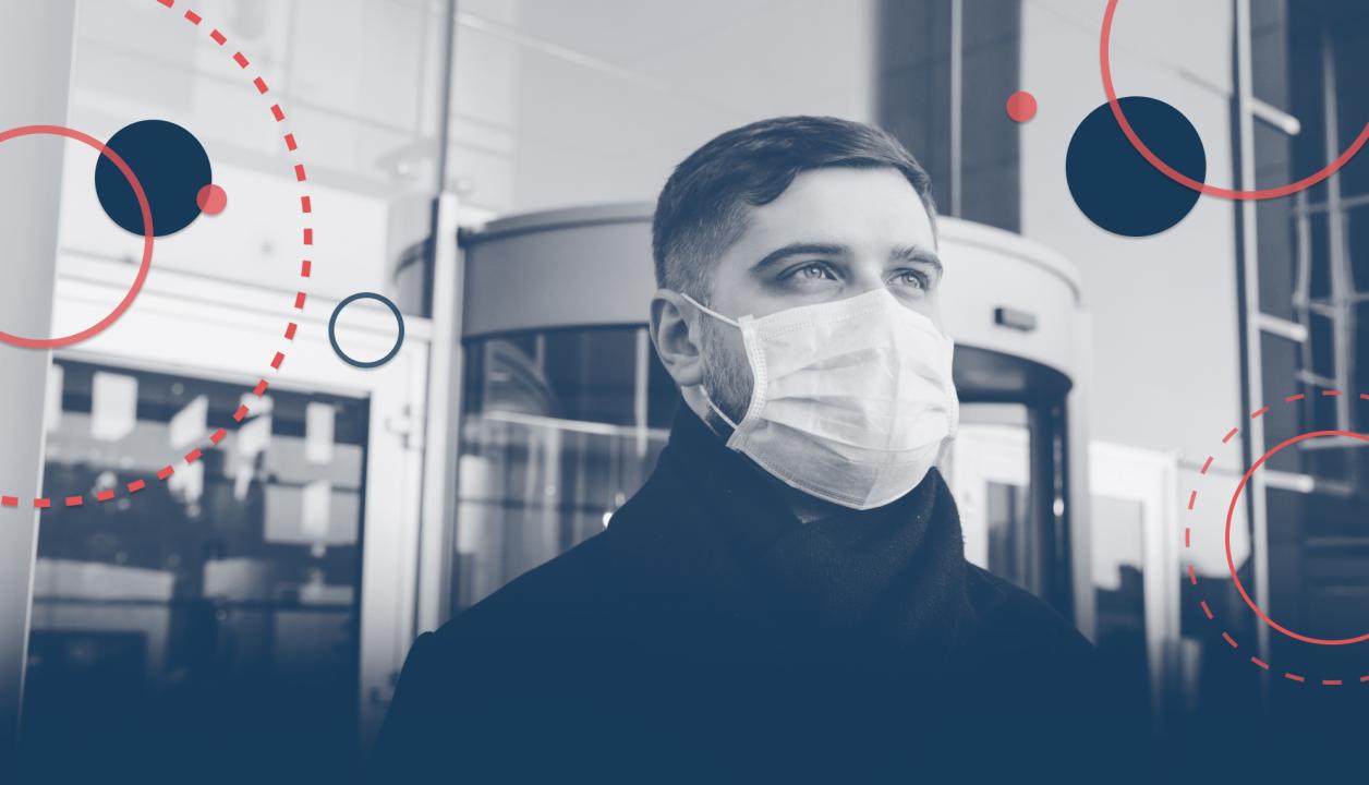 un homme portant un masque devant un immeuble de bureaux