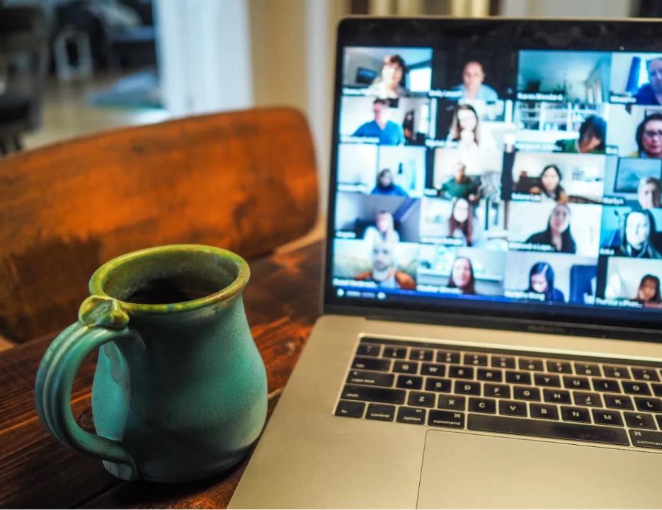 Coffee mug and laptop displaying a team meeting. 