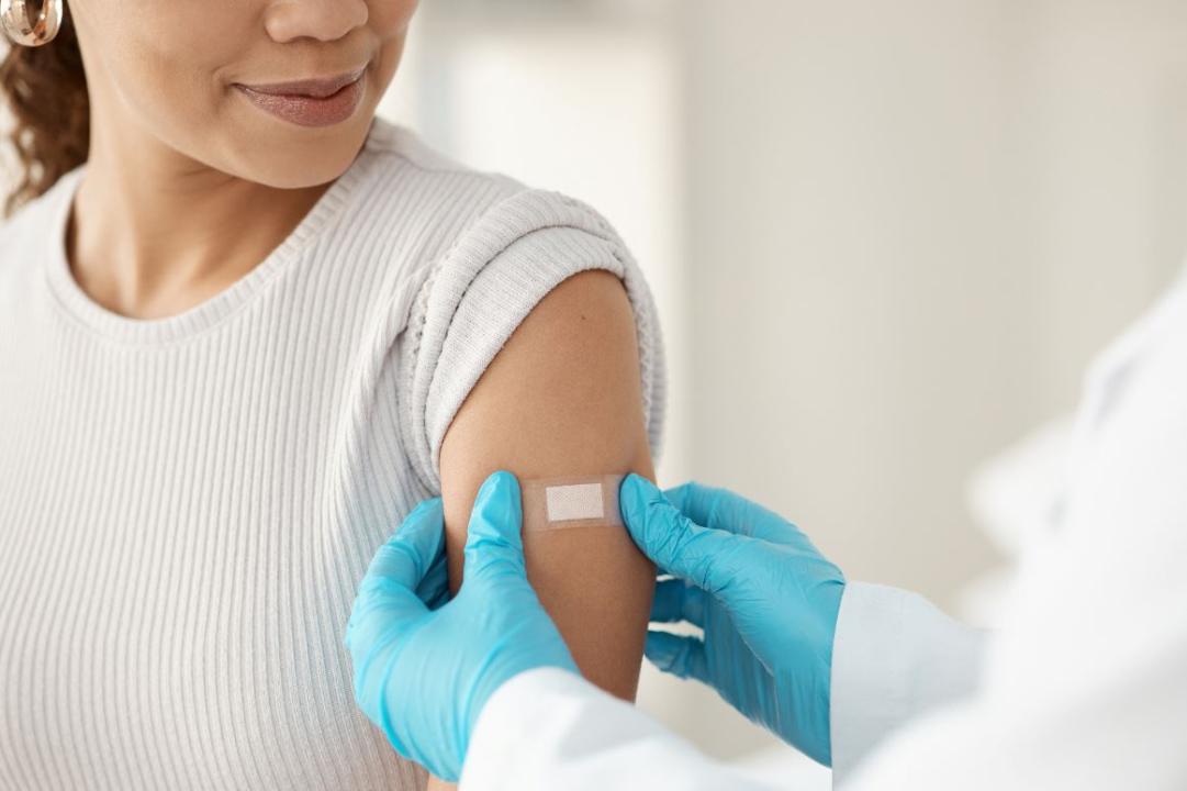 A woman getting a bandaid on her shoulder 