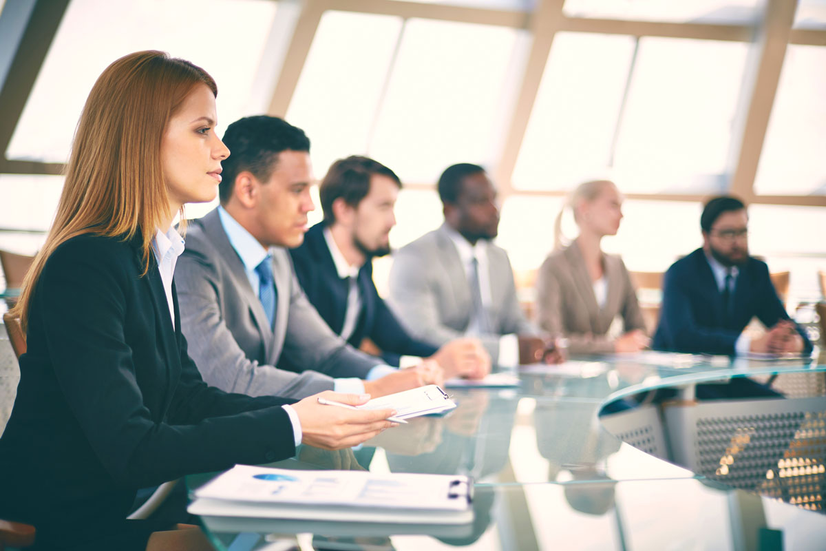 group of people in business attire paying attention to a lecture