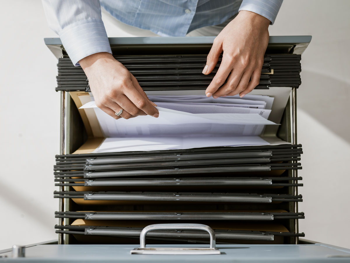 person sorting papers in a folder of a filing cabinet