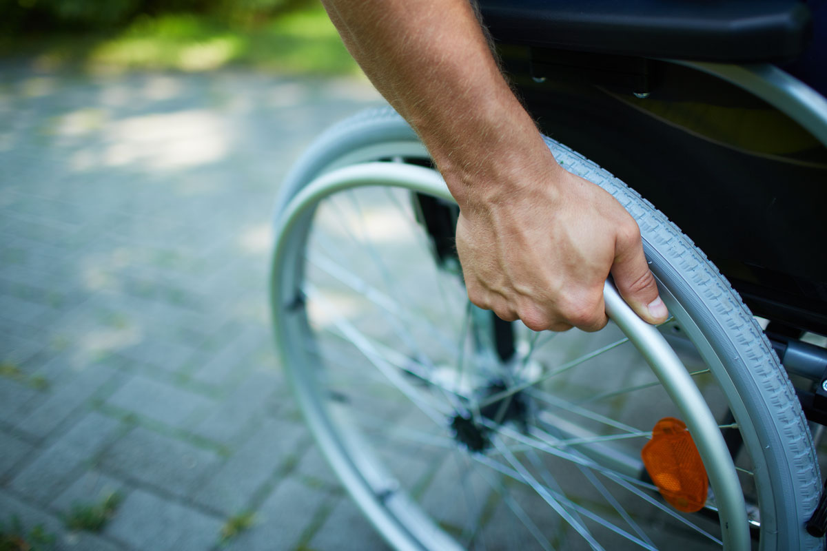 closeup of hand of disabled person on their wheelchair's wheel