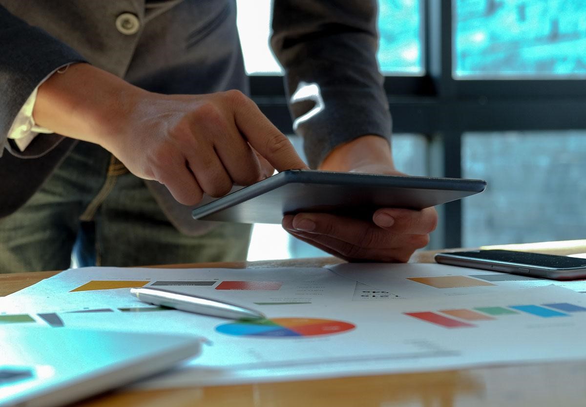 closeup of someone using a phone over reports on a desk 