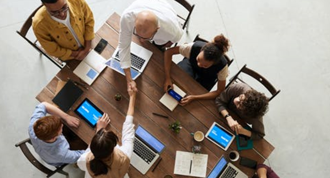 Six people sitting at a desk working together 