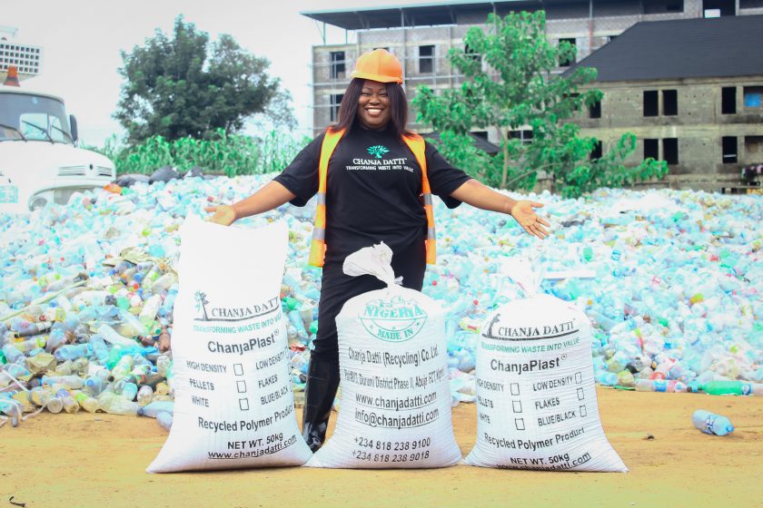 >Chanja Datti team member in front of a large pile of plastics for recycling 