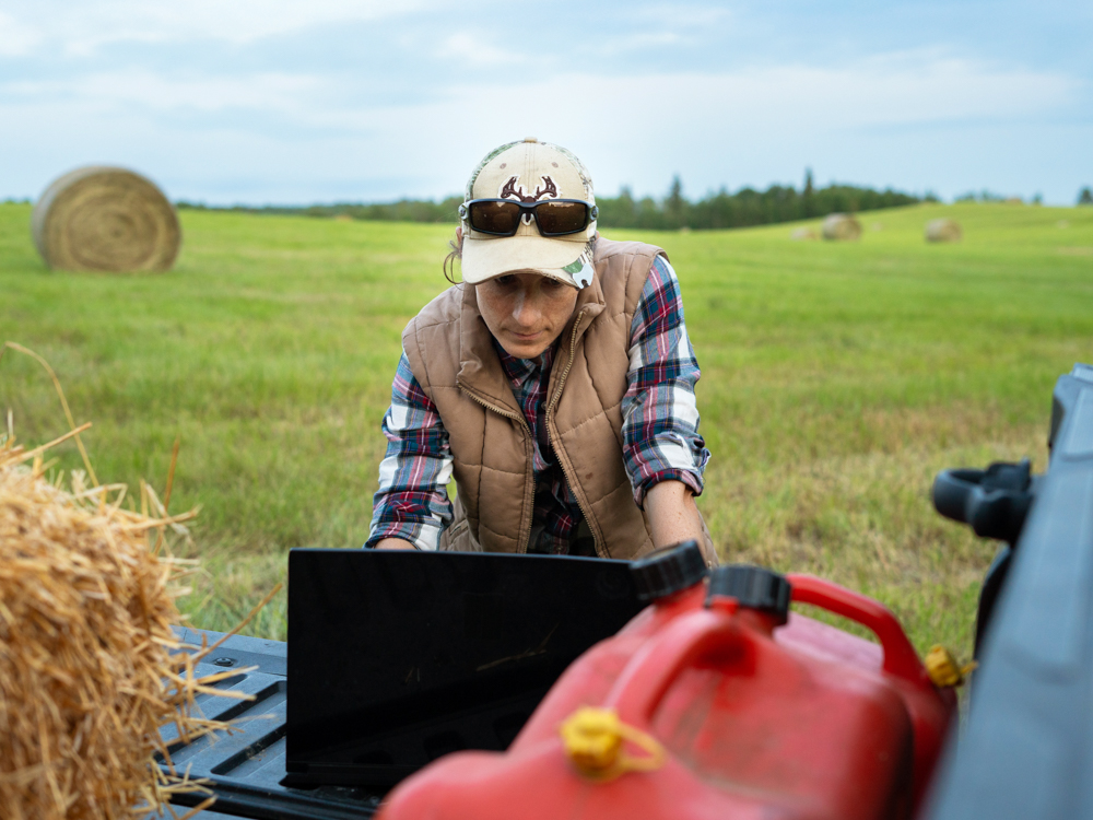 Female farmer on laptop in farm field