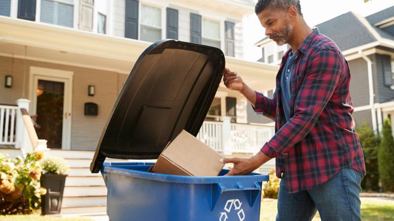 man filling a recycle bin outside