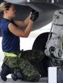 Female armed forces member working under a fighter jet